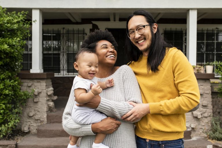 A family smiles outside of their new house