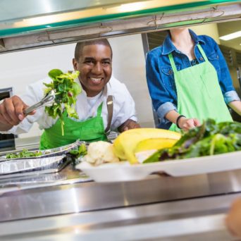 A cafeteria worker serves healthy food