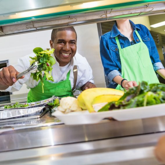 A cafeteria worker serves healthy food