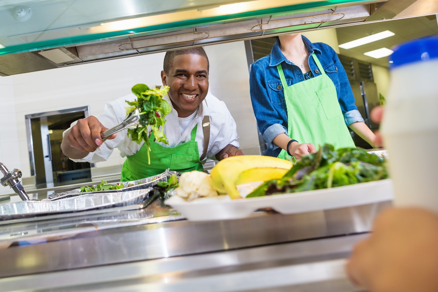 A cafeteria worker serves healthy food